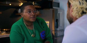 Movie still from “You People” (2023), directed by Kenya Barris – A person sitting in front of a refrigerator wearing glasses; Close Up shot, Over the shoulder angle