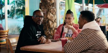 Movie still from “You People” (2023), directed by Kenya Barris – A group of people sitting at a table with drinks; Medium shot, Over the shoulder angle