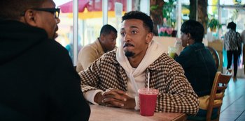 Movie still from “You People” (2023), directed by Kenya Barris – A man sitting at a table with a cup of coffee; Medium shot, Over the shoulder angle
