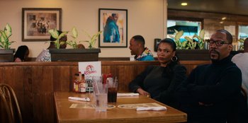 Movie still from “You People” (2023), directed by Kenya Barris – A woman sitting at a table in front of a man; Medium shot, Over the shoulder angle