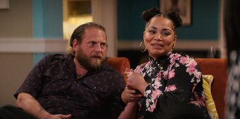 Movie still from “You People” (2023), directed by Kenya Barris – A man and a woman sitting next to each other on a couch; Medium shot, Over the shoulder angle