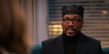 Movie still from “You People” (2023), directed by Kenya Barris – An older man wearing glasses and a black hat; Close Up shot, Over the shoulder angle