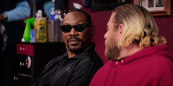 Movie still from “You People” (2023), directed by Kenya Barris – A man with a beard and sunglasses sitting next to another man with long blonde hair; Close Up shot, Over the shoulder angle