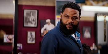 Movie still from “You People” (2023), directed by Kenya Barris – A man standing in a room next to pictures; Close Up shot, Over the shoulder angle