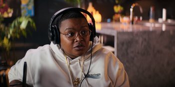 Movie still from “You People” (2023), directed by Kenya Barris – A person wearing headphones and a white hoodie; Close Up shot, Over the shoulder angle