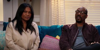 Movie still from “You People” (2023), directed by Kenya Barris – A woman and a man sitting next to each other on a couch; Medium shot, Over the shoulder angle