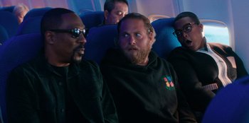 Movie still from “You People” (2023), directed by Kenya Barris – A group of people sitting on a plane; Medium shot, Over the shoulder angle
