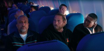 Movie still from “You People” (2023), directed by Kenya Barris – A group of people sitting on a plane; Medium shot, High angle