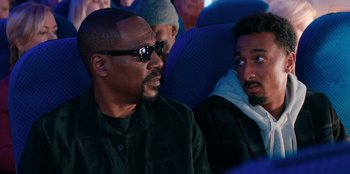 Movie still from “You People” (2023), directed by Kenya Barris – Two men sitting on a blue airplane looking at something; Close Up shot, Over the shoulder angle