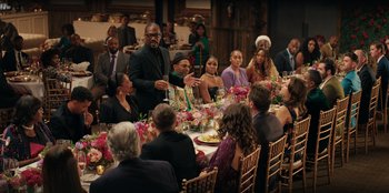 Movie still from “You People” (2023), directed by Kenya Barris – A group of people sitting around a table at a party; Wide shot, Over the shoulder angle