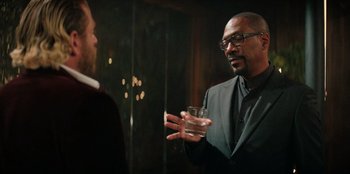 Movie still from “You People” (2023), directed by Kenya Barris – A man talking to another man holding a glass of water; Medium shot, Over the shoulder angle