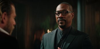 Movie still from “You People” (2023), directed by Kenya Barris – A person wearing a suit and glasses; Close Up shot, Over the shoulder angle