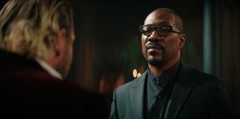 Movie still from “You People” (2023), directed by Kenya Barris – A man wearing a suit and glasses is talking to another man in a suit; Close Up shot, Over the shoulder angle