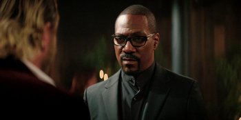 Movie still from “You People” (2023), directed by Kenya Barris – A person wearing a suit and glasses; Close Up shot, Over the shoulder angle