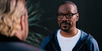 Movie still from “You People” (2023), directed by Kenya Barris – A man wearing glasses and a white t - shirt is talking to another man; Close Up shot, Over the shoulder angle