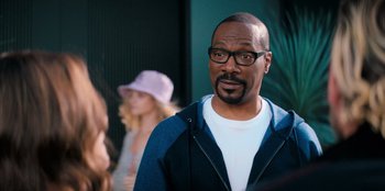 Movie still from “You People” (2023), directed by Kenya Barris – A person wearing glasses and a hat; Close Up shot, Over the shoulder angle