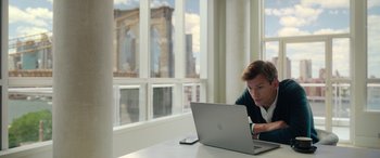Movie still from “Your Place or Mine” (2023), directed by Aline Brosh McKenna – A man sitting in front of an open laptop computer; Medium shot, Over the shoulder angle