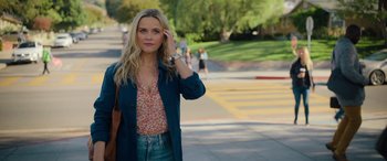 Movie still from “Your Place or Mine” (2023), directed by Aline Brosh McKenna – A beautiful young woman standing on a sidewalk next to a street; Medium shot, Over the shoulder angle