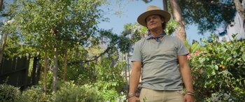 Movie still from “Your Place or Mine” (2023), directed by Aline Brosh McKenna – A man wearing a hat standing next to a tree; Medium shot, Over the shoulder angle