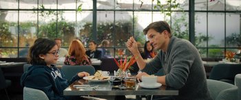 Movie still from “Your Place or Mine” (2023), directed by Aline Brosh McKenna – A man sitting at a table in front of a bunch of other people; Medium shot, Over the shoulder angle