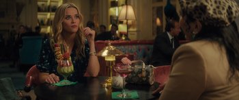 Movie still from “Your Place or Mine” (2023), directed by Aline Brosh McKenna – A woman sitting at a table with a glass of wine; Medium shot, Over the shoulder angle