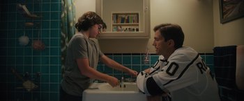 Movie still from “Your Place or Mine” (2023), directed by Aline Brosh McKenna – A man and a boy in a bathroom with a sink and tiled walls; Medium shot, Over the shoulder angle