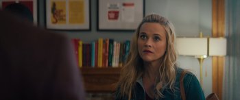 Movie still from “Your Place or Mine” (2023), directed by Aline Brosh McKenna – A person sitting in front of a bunch of books; Close Up shot, Over the shoulder angle