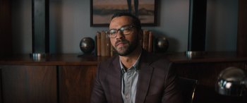 Movie still from “Your Place or Mine” (2023), directed by Aline Brosh McKenna – A man wearing a suit and glasses sitting in front of a wall; Close Up shot, Low angle