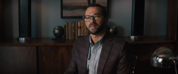 Movie still from “Your Place or Mine” (2023), directed by Aline Brosh McKenna – A man in a suit and glasses sitting in front of books; Close Up shot, Over the shoulder angle