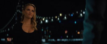 A woman standing in front of a city skyline at night