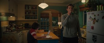 Movie still from “Your Place or Mine” (2023), directed by Aline Brosh McKenna – A man is drinking a beverage while a woman works on a laptop; Medium shot, Over the shoulder angle