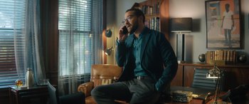 Movie still from “Your Place or Mine” (2023), directed by Aline Brosh McKenna – A man sitting on a chair talking on a phone; Medium shot, Over the shoulder angle