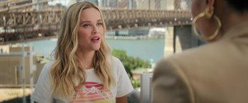 Movie still from “Your Place or Mine” (2023), directed by Aline Brosh McKenna – A woman sitting at a table in front of a bridge; Close Up shot, Over the shoulder angle
