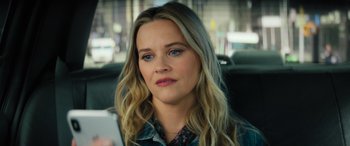 Movie still from “Your Place or Mine” (2023), directed by Aline Brosh McKenna – A person sitting in a car holding a cell phone; Close Up shot, High angle