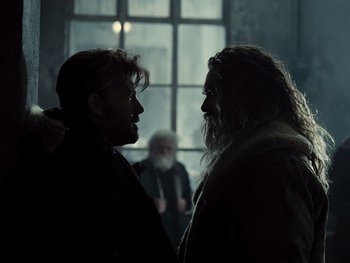 Movie still from “Zack Snyder's Justice League” (2021), directed by Zack Snyder – Two men are facing each other in a dark room; Medium shot, Over the shoulder angle