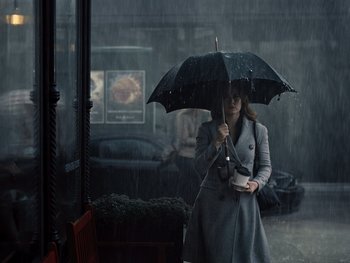 Movie still from “Zack Snyder's Justice League” (2021), directed by Zack Snyder – A woman holding an umbrella while standing in the rain; Wide shot, Low angle