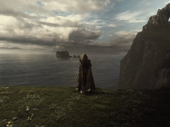 Movie still from “Zack Snyder's Justice League” (2021), directed by Zack Snyder – A person sitting on top of a grass covered hill; Wide shot, High angle