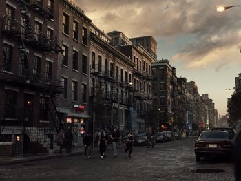 Movie still from “Zack Snyder's Justice League” (2021), directed by Zack Snyder – A group of people walking down a street near buildings; Extreme Wide shot, High angle