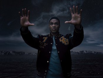 Movie still from “Zack Snyder's Justice League” (2021), directed by Zack Snyder – A young man in a baseball jacket holding his hands up in the air; Medium shot, Overhead angle