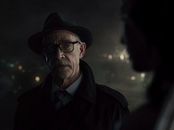 Movie still from “Zack Snyder's Justice League” (2021), directed by Zack Snyder – An older man wearing a black hat and glasses; Close Up shot, Over the shoulder angle