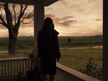 Movie still from “Zack Snyder's Justice League” (2021), directed by Zack Snyder – A woman standing on a porch looking out at a field; Extreme Wide shot, Over the shoulder angle