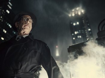 Movie still from “Zack Snyder's Justice League” (2021), directed by Zack Snyder – A man in a black coat and hat standing in front of a building at night; Medium shot, Low angle
