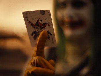 Movie still from “Zack Snyder's Justice League” (2021), directed by Zack Snyder – A person holding up a joker playing card in front of their face; Extreme Close Up shot, Low angle
