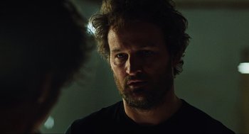 Movie still from “Zero Dark Thirty” (2012), directed by Kathryn Bigelow – A person wearing a black t - shirt; Close Up shot, Over the shoulder angle