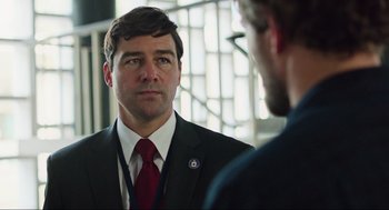 Movie still from “Zero Dark Thirty” (2012), directed by Kathryn Bigelow – A man in a suit and tie looking at himself in the mirror; Close Up shot, Over the shoulder angle