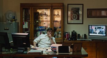 Movie still from “Zero Dark Thirty” (2012), directed by Kathryn Bigelow – A man sitting at a desk in front of a book case; Medium shot, High angle