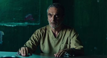 Movie still from “Zero Dark Thirty” (2012), directed by Kathryn Bigelow – An older man sitting at a table in a room; Medium shot, Over the shoulder angle