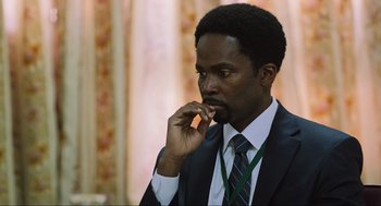 Movie still from “Zero Dark Thirty” (2012), directed by Kathryn Bigelow – A man in a suit and tie holding his hand to his face; Close Up shot, Over the shoulder angle