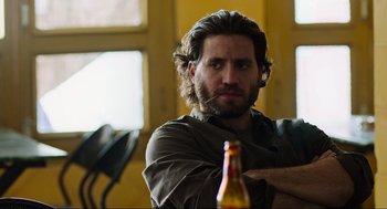 Movie still from “Zero Dark Thirty” (2012), directed by Kathryn Bigelow – A man with long hair and a beard sitting in front of a beer bottle; Close Up shot, Over the shoulder angle