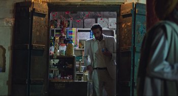 Movie still from “Zero Dark Thirty” (2012), directed by Kathryn Bigelow – A man standing in a doorway of a store holding a cell phone; Wide shot, Over the shoulder angle